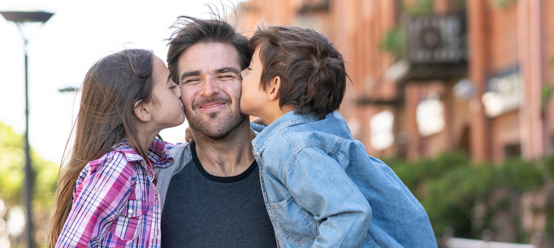 daughter and son kissing their dad on the cheeks