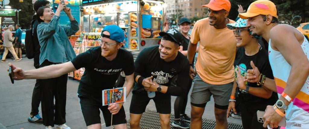 Five adults pose for a picture on the street, dressed in running attire